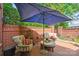 Charming brick patio with comfortable seating, a blue umbrella, and lush greenery, ideal for outdoor relaxation at 3128 Ethereal Ln, Charlotte, NC 28226