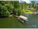 Aerial view of a property with a dock and boat lift on the lake, surrounded by green landscape at 335 Whisper Lake Dr, New London, NC 28127