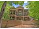 Multi-story home with stone accents, balconies, and a tiered patio surrounded by lush trees at 335 Whisper Lake Dr, New London, NC 28127