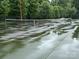 A public wet tennis court surrounded by tall green trees at 405 W Ormand Ave, Bessemer City, NC 28016