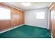 Cozy bedroom with natural light, wood paneled walls, and green carpet at 4268 Wilkesboro Hwy, Statesville, NC 28625