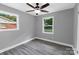 Neutral bedroom featuring light gray walls, light wood-look flooring, and well-lit windows with ceiling fan at 4914 Ridgeley Dr, Charlotte, NC 28208