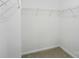 Organized walk-in closet with white shelving and neutral carpet flooring at 6322 Sydney Mae Ln, Charlotte, NC 28262