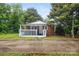 Charming brick home featuring a cozy, covered front porch with white railings, surrounded by lush greenery at 653 Turner St, Mooresville, NC 28115