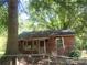 Exterior view of a small weathered home with a chainlink fence, surrounded by overgrown trees at 711 East Dr, Cherryville, NC 28021