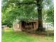 Exterior shot of a small weathered home surrounded by trees, with a chainlink fence at 711 East Dr, Cherryville, NC 28021