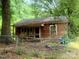 Exterior shot of a small home featuring weathered siding, surrounded by overgrown trees and a chainlink fence at 711 East Dr, Cherryville, NC 28021