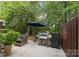 Back patio with grill, shade umbrella and outdoor seating near a wooded area at 10206 Linksland Dr, Huntersville, NC 28078