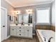 Bright bathroom with double sinks, large mirror, soaking tub with tile accents and contemporary fixtures at 10515 Royal Winchester Dr, Charlotte, NC 28277