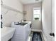 Well-lit laundry room featuring modern washer and dryer, sink, overhead rack and a window at 10515 Royal Winchester Dr, Charlotte, NC 28277