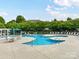 Inviting community pool area with lounge chairs, umbrellas, tables and a white pergola on the left side at 10515 Royal Winchester Dr, Charlotte, NC 28277
