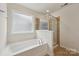 Bright bathroom featuring a tub and shower with neutral tile and a frosted window at 107 Sequoia St, Mooresville, NC 28117