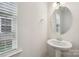 Modern powder room featuring a pedestal sink, oval mirror, and window with natural light at 107 Sequoia St, Mooresville, NC 28117