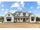 Beautiful two-story farmhouse with a covered porch, black window accents and well manicured landscaping at 111 Monbo Meadows Ln, Statesville, NC 28677