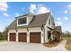 Attached three-car garage featuring carriage-style doors and charming exterior finishes at 111 Monbo Meadows Ln, Statesville, NC 28677