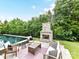 Gorgeous backyard pool with stone fireplace and patio seating area surrounded by green landscaping at 121 Enclave Meadows Ln, Matthews, NC 28104