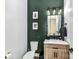 Stylish powder room with wood vanity, modern fixtures, and elegant green accent wall at 121 Enclave Meadows Ln, Matthews, NC 28104