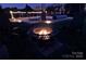 Inviting backyard featuring a stone patio with fire pit and stylish outdoor seating under soft string lights at 137 Flora Vista Dr, Mooresville, NC 28117