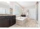 Luxurious bathroom with a soaking tub and dark wood vanities at 14228 Twin Eagles Ln, Charlotte, NC 28278