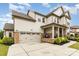 Beige two-story home with stone accents, an attached garage, and manicured landscaping at 14228 Twin Eagles Ln, Charlotte, NC 28278