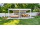 A spacious outdoor patio under a pergola with comfortable seating and dining areas, set amidst a well-manicured lawn at 1446 Downs Ave, Charlotte, NC 28205