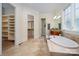 Primary bathroom displaying a soaking tub, tile flooring, and access to walk-in closets at 1500 Tarrington Way, Wesley Chapel, NC 28079