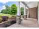 Covered porch featuring stone columns, brick flooring, and landscaped garden views at 1500 Tarrington Way, Wesley Chapel, NC 28079