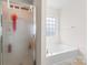 Bathroom with a glass door shower, and a soaking tub with a large window at 1911 Savannah Hills Dr, Matthews, NC 28105