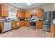 Well-lit kitchen featuring oak cabinetry, stainless steel appliances, and modern laminate flooring at 1911 Savannah Hills Dr, Matthews, NC 28105
