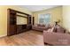 Spacious living room with wood-look flooring, a large entertainment center, and comfortable seating by a bright window at 1911 Savannah Hills Dr, Matthews, NC 28105