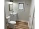 Clean, bright bathroom with a vanity, toilet, mirror, and window with wood grain vinyl flooring at 216 N Vance St, Gastonia, NC 28052