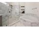 Elegant bathroom featuring marble finishes, a glass-enclosed shower, and a luxurious soaking tub at 229 N Church St # 204, Charlotte, NC 28202