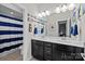 Bathroom with double vanity, large mirror, and shower/tub combination with striped curtain at 2414 Madeira Cir, Waxhaw, NC 28173