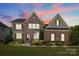 Charming two-story stone home featuring a well-manicured front yard at dusk at 2414 Madeira Cir, Waxhaw, NC 28173