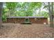Home backyard featuring a brick home and a small deck surrounded by mature trees at 403 Cherrywood Ln, Albemarle, NC 28001