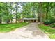 View of the home showing the driveway leading to the residence surrounded by lush trees at 403 Cherrywood Ln, Albemarle, NC 28001