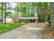 Inviting brick home with a long driveway, carport, and verdant lawn, surrounded by mature trees offering shade and privacy at 403 Cherrywood Ln, Albemarle, NC 28001