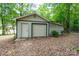 Detached one-car garage with white door in wooded backyard at 403 Cherrywood Ln, Albemarle, NC 28001