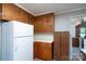 A view of the kitchen with wooden cabinetry and white appliances, and pass-through to another room at 403 Cherrywood Ln, Albemarle, NC 28001