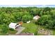 An aerial view of the property with barns, sheds, a red utility house, and mature trees at 4335 E Nc 10 Hwy, Claremont, NC 28610
