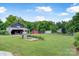 Spacious backyard with a large garage, red shed, open lawn area, and mature trees at 4335 E Nc 10 Hwy, Claremont, NC 28610