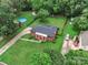 Stunning aerial view of a brick home featuring a pool, expansive yard, mature trees, and additional buildings at 5633 Mallard S Dr, Charlotte, NC 28227
