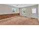 Bedroom features neutral carpet, brick accent wall, natural light from two windows, and a white exterior door at 5633 Mallard S Dr, Charlotte, NC 28227