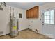 Laundry room with a utility sink, overhead cabinet, water heater, and access to the exterior at 5633 Mallard S Dr, Charlotte, NC 28227