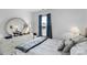 Bright and airy bedroom with gray and white bedding and a large round mirror at 6104 Follow The Trl, Indian Trail, NC 28079