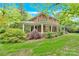 Classic brick home with a sprawling front porch, surrounded by mature trees and a green lawn at 634 E Center Ave, Mooresville, NC 28115