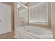 Relaxing bathroom featuring a jetted tub, a window with blinds, and a door at 6614 Truman St, Indian Trail, NC 28079