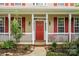 Inviting front porch with a red front door, white columns and railings, framed by lush landscaping at 6614 Truman St, Indian Trail, NC 28079