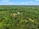 Expansive aerial view highlighting a serene rural property with a red barn-style house nestled in a dense forest at 925 Hamilton Rd, Chester, SC 29706