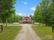 Majestic red barn with white trim sits at the end of a long driveway, surrounded by trees and a white fence at 925 Hamilton Rd, Chester, SC 29706